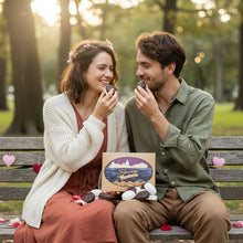 Load image into Gallery viewer, Box of Tripicians Coconut and chocolate covered coconut macaroons being enjoyed by a yound couple on a park bench decorated valentine's day