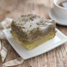 Load image into Gallery viewer, Square piece of crumb cake with a streusel crumbly topping on a white plate, served with a cup of coffee.
